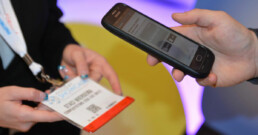 Smartphone scanning attendee's badge at a tradeshow, showcasing seamless event technology for efficient check-ins and data retrieval.