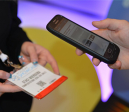 Smartphone scanning attendee's badge at a tradeshow, showcasing seamless event technology for efficient check-ins and data retrieval.