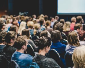 A large group of attendees sitting in a lecture hall at a business event