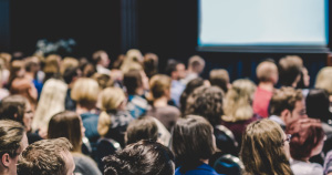 A large group of attendees sitting in a lecture hall at a business event